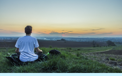 a man sitting in meditation in a field